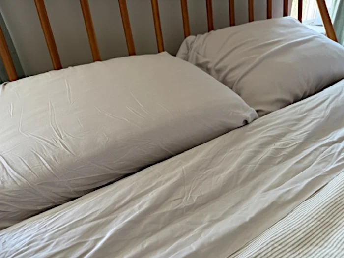 Bedroom scene image brief showing LUXOME Luxury Sheet Set on a queen bed in a warm-climate bedroom with fan airflow and thin duvet layer