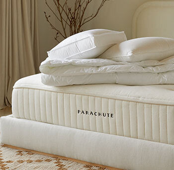 Bedroom scene image brief showing Parachute Classic Percale Sheet Set on a queen bed in a warm-climate bedroom with fan airflow and thin duvet layer