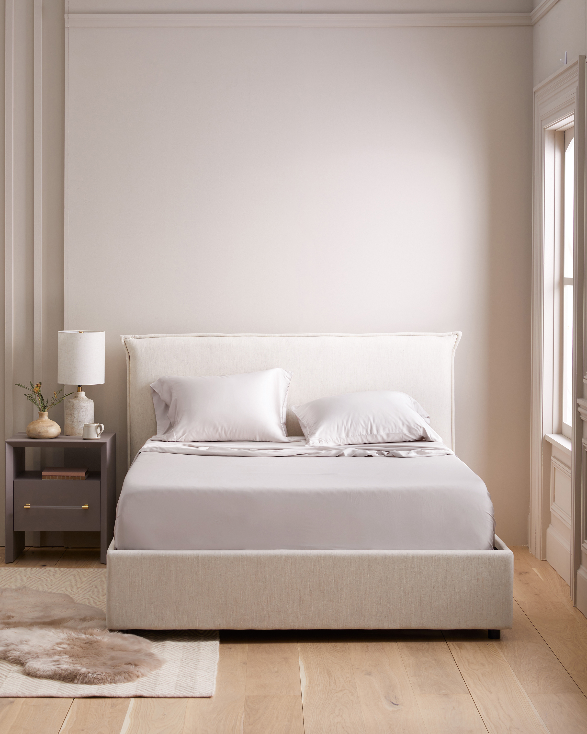 Bedroom scene image brief showing Quince Bamboo Sheet Set on a queen bed in a warm-climate bedroom with fan airflow and thin duvet layer